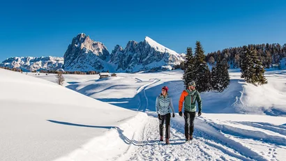 Zwei Wanderer im Schnee mit Bergpanorama und klarem blauem Himmel