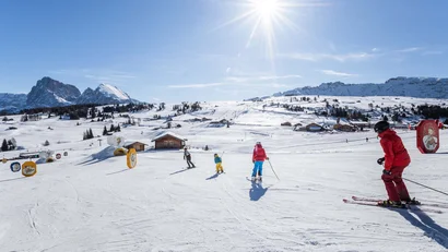 Familie beim Skifahren an sonnigem Tag im Schnee mit Bergen im Hintergrund