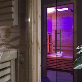 Moderner Saunaraum mit beleuchtetem Innenraum und Handtüchern auf der Bank