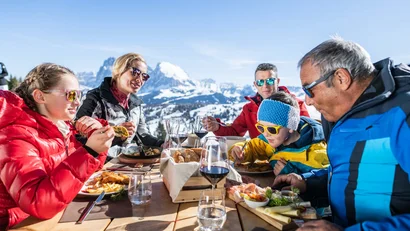 Famiglia che pranza all'aperto con vista sulle montagne innevate